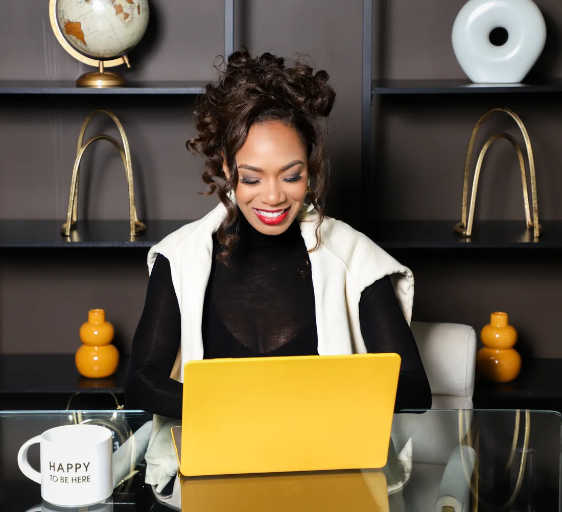 Damali Alexander smiling as she works on a yellow laptop